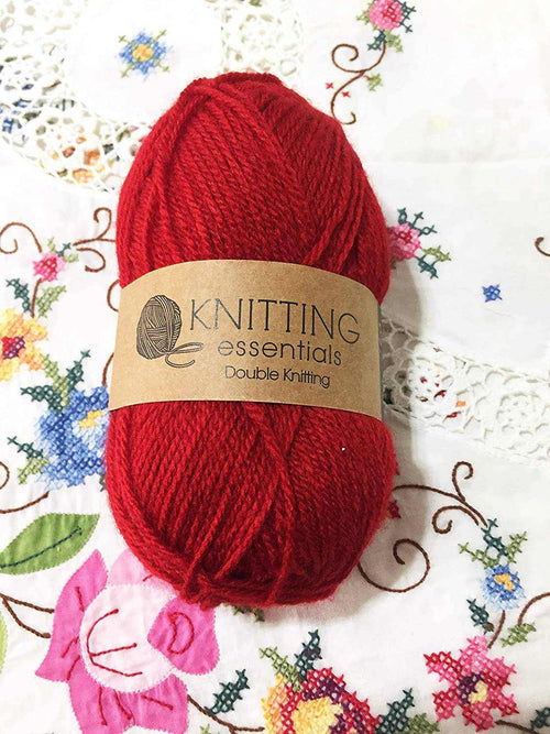 Red double knitting yarn ball with knitting essentials label on floral fabric background