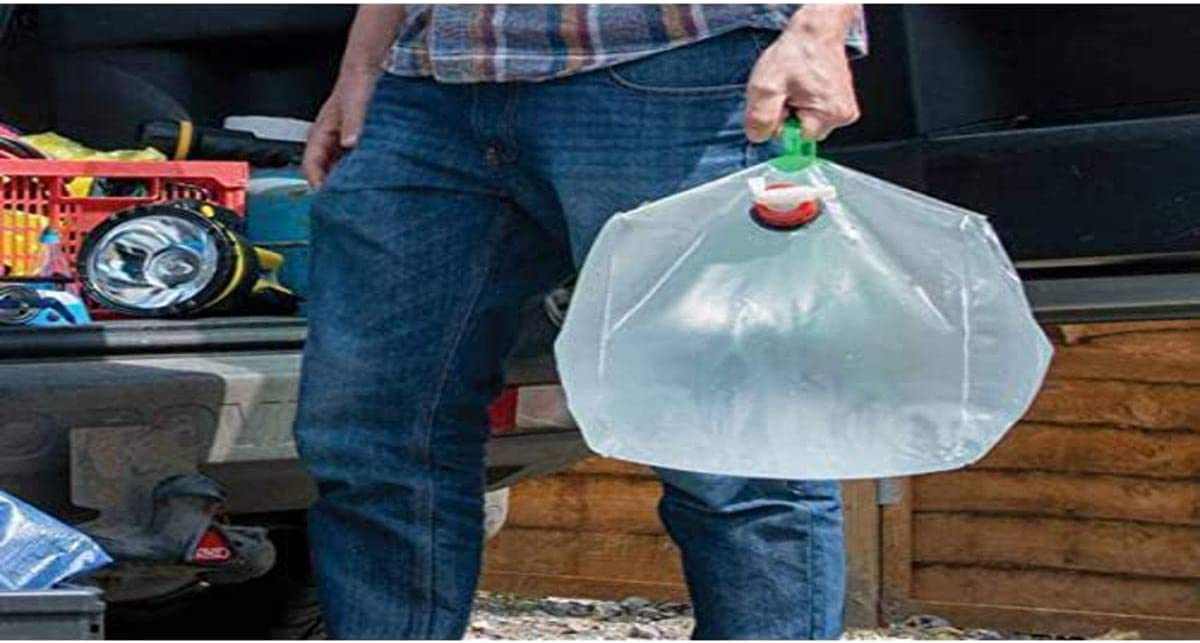 Silverline 159729 collapsible 20L water container with green handle and twist tap being carried outdoors